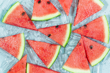 watermelon and ice,Beautiful poster with Sliced red watermelon closeup. Group Triangle pieces of watermelon on ice blue background. Bright Food wallpaper of fresh watermelon. Top view. Flat lay.