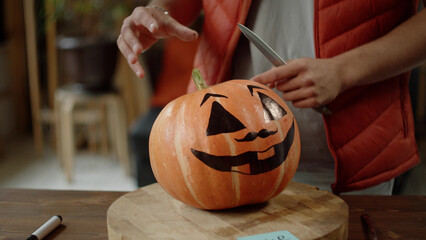 A man is explaining his friends how to carve the top of the halloween pumpkin