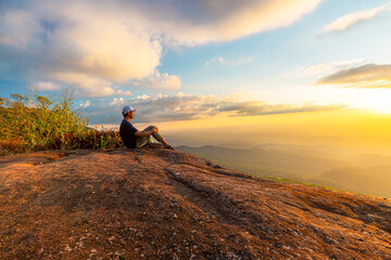 man sitting on the cliff,Young man sitting on the cliff and looking on the valley