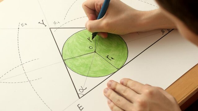 Young mathematician hands marks the radius of green circle in triangle. Date of shooting day 27 January 2022 year, MSK time. This video was filmed in Russia.