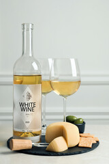 Bottle of white wine, glasses and crackers with cheese on table