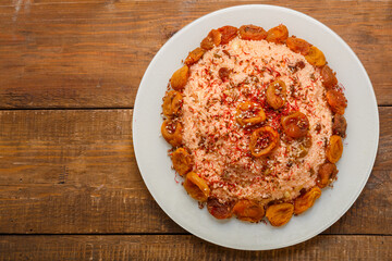 Masfouf from couscous on almond milk with dried fruits and nuts in a plate on a wooden table.