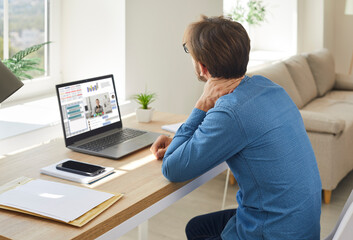 Businessman sit at desk work online on laptop at home suffer from backache from incorrect posture....