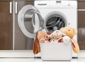 Children's toys in a laundry basket on the background of a washing machine.