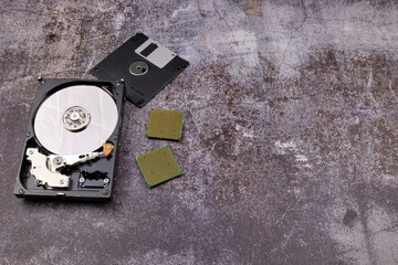 Composition of various computer components on a dark background similar to cement, different computer components such as hard drives, disk drives, graphic controller, micro chips, fans and heat sinks.