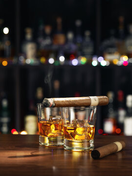 Closed up view of glass of whiskey with cigar on top on color back