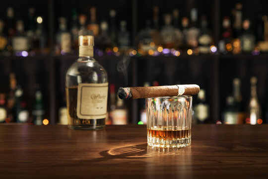 NO LOGOS OR TRADEMARKS!  SELF MADE LABELS! close up view of cigar, bottle of whiskey and a glass aside on color back. 