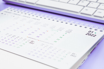 Paper present calendar for January 2022 with keyboard lie on a light lilac
