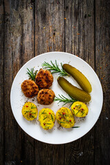 Roast meatballs with boiled potatoes and pickled cucumbers on wooden table
