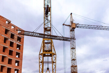 Tower cranes on construction site near brick house