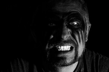 Fototapeta premium Viking man with a furious gaze and a painted face looks into the darkness with bright eyes