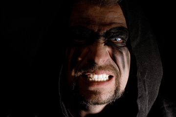 Fototapeta premium Viking man with a furious gaze and a painted face looks into the darkness with bright eyes