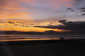 Dramatic sunset sky with clouds. Dramatic sunset over the sea with silhouettes of people by the beach