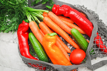 Seasonal vegetables: carrots, peppers and tomato in a gray cotton mesh .