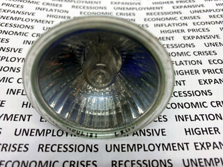 Light spot bulb closeup view on a paper with text economic crises, recession, unemployment