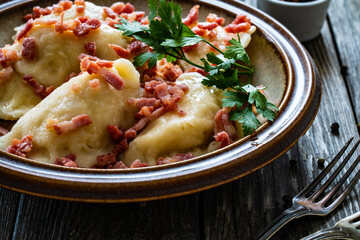 Dumplings - cheese noodles with onion and bacon on wooden background
