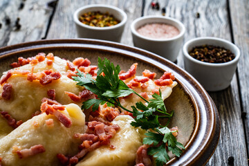Dumplings - cheese noodles with onion and bacon on wooden background
