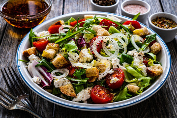 Fresh Greek salad - feta cheese, cherry tomatoes, cucumber, black olives and onion on wooden table
