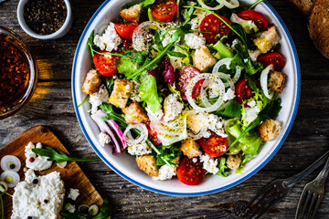 Fresh Greek salad - feta cheese, cherry tomatoes, cucumber, black olives and onion on wooden table
