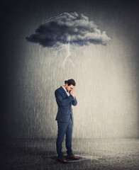 Pessimistic and depressed businessman standing under rain as the negative thoughts stands over his head like a storm cloud. Person suffering anxiety and headache. Concept for emotional crisis - obrazy, fototapety, plakaty