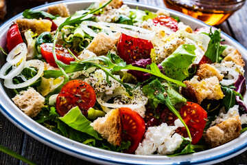 Fresh Greek salad - feta cheese, cherry tomatoes, cucumber, black olives and onion on wooden table
