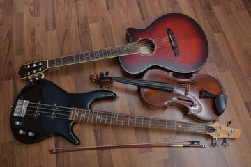 Eine dunkel rote Gitarre, ein schwarzer E-Bass Gitarre und eine braune Violine (Viola) mit Bogen...