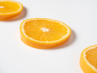 Fototapeta na wymiar Close-up of three slices of ripe orange laid out on a white background. Delicious beautiful fruit full of vitamins. Studio shot, side view