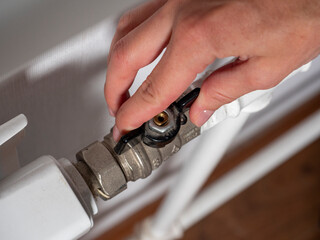 A woman's hand on the valve of the central heating battery. The concept of heat overlap, the crisis...