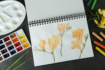 Flat lay composition with beautiful drawing of freesia flowers on black table
