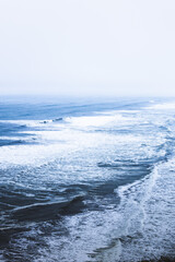 Naklejka na ściany i meble Waves of a blue sea breaking on the shore of the beach