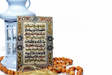 Selective focus of Ramadan fanous lantern, Islamic rosary and Al Kursi verse, the greatest verse in Quran, Translation (Allah, There is no god but He, the living, the self- subsisting, the eternal)