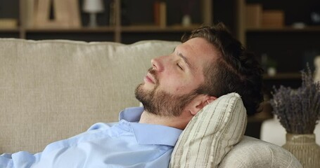 Closeup head shot calm tranquil young man sleep on cozy sofa take break to have some rest at daytime. Serene millennial male nap dream on couch with closed eyes take comfortable position enjoy relax