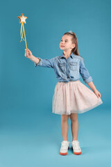 Cute girl in diadem with magic wand on light blue background. Little princess