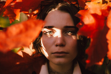 Portrait of teenage girl standing among red leaves during autumn