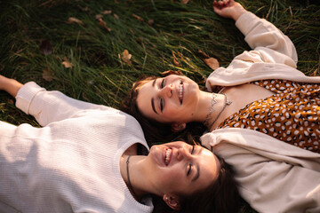 Two happy young women smiling while lying on grass