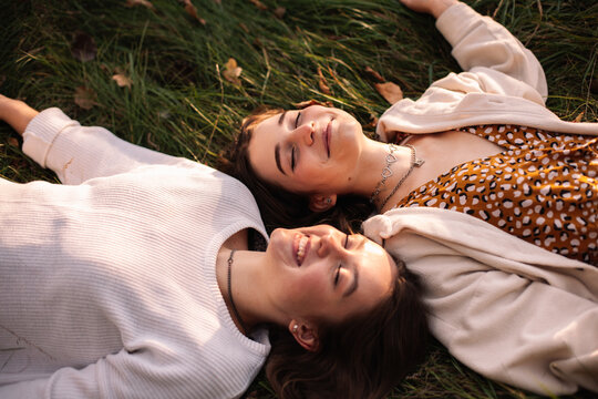 Two happy teenage girls smiling while lying on grass with eyes closed