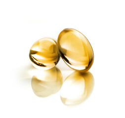 Two vitamin d capsules on a smooth white background close-up with selective focus. Macro photo of...