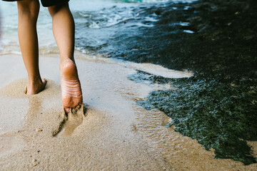 Boys feet in wet beach sand on the edge of the ocean