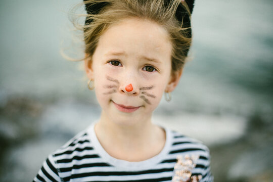 Brown eyed girl with cat face painted on