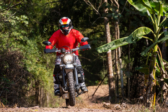Man riding his scrambler type motorcycle on rugged terrain in Thailand
