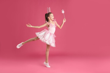 Cute girl in fairy dress with crown and magic wand on pink background, space for text. Little princess © New Africa
