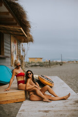Young women in bikini sitting by the surf cabin on a beach at summer day