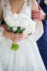 Hands of the bride close-up with a bouquet of fresh beautiful flowers. Attribute of the bride