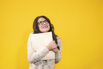 happy beautiful young woman on isolated yellow background looking up, woman happy to release her...