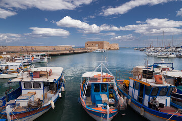Fototapeta na wymiar Ancient Venetian harbor with yachts and boats and fortress Koules in background, Heraklion, Greece