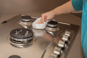 Young woman cleaning the hob. Household cleaning at home