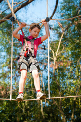 young boy navigating treetop ropes course