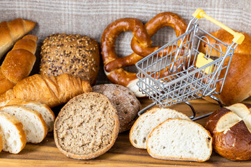 empty mini shopping cart, Different types of bread around the concept, Rising prices for baked goods