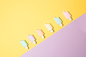 Ice cream sticks on pastel colors background., flat lay. Trendy sunlight Summer pattern made with popsicle ice cream on bright light background. Minimal summer concept.
