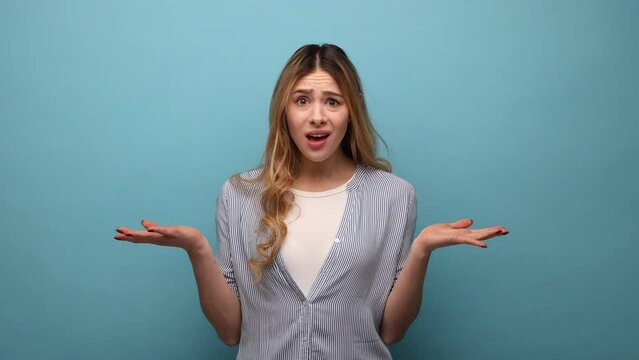 How could you. Portrait of annoyed angry woman raising arms, indignantly asking reason of failure, quarreling, wearing striped shirt. Indoor studio shot isolated on blue background.